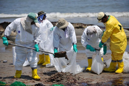 照片拍摄于2010年5月24日,在美国路易斯安那州南部的佛琼港,清洁工人正在清理海滩上的油污。新华社记者张军摄