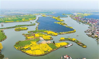 工作人员在江苏泰州海陵区华港镇下溪村乘船巡检水上光伏设备。汤德宏摄（人民视觉）